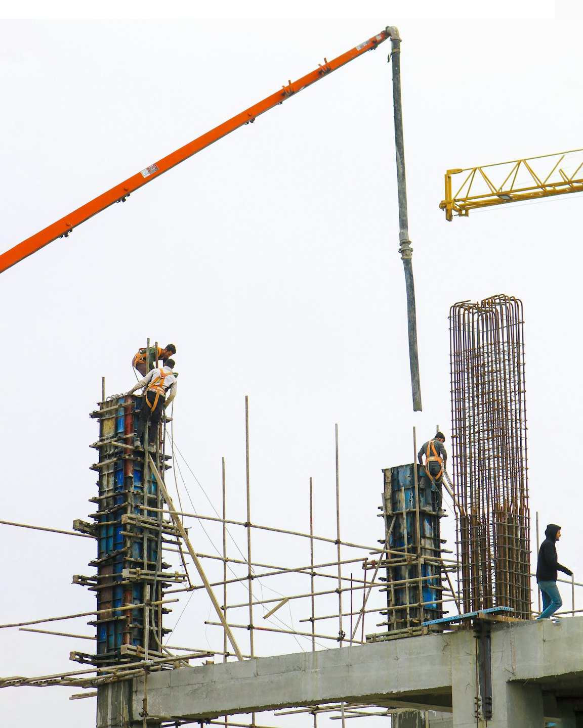 Bauarbeiter gießen Beton aus einer Betonpumpe an einem unfertigen Gebäude.